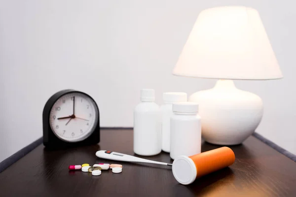 Medicamentos, relógio e lâmpada — Fotografia de Stock