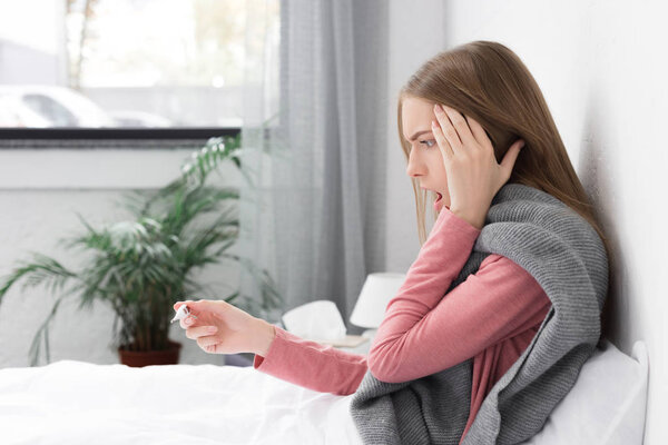 шокированная девушка смотрит на термометр
