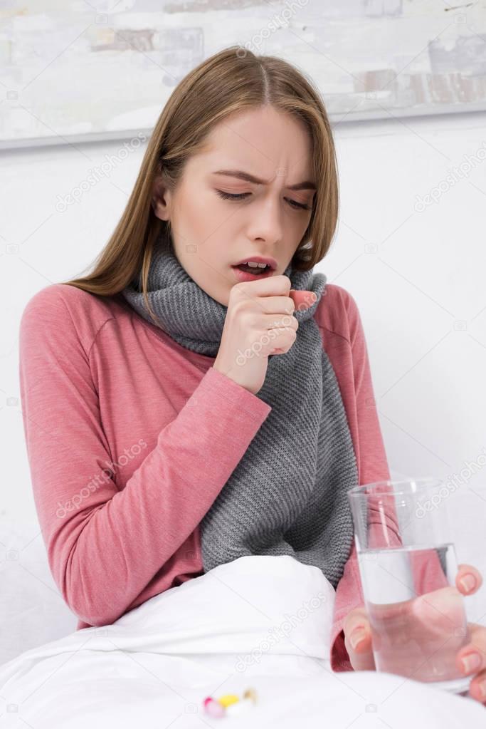 coughing woman with water and pills