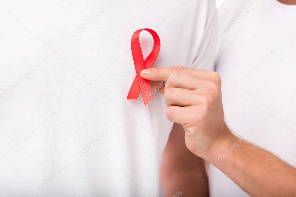 man attaching aids ribbon on t-shirt