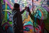 pouliční umělec Malování graffiti s aerosolové barvy na zeď v noci