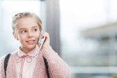 dítě mluví na smartphone proti okno během dne 