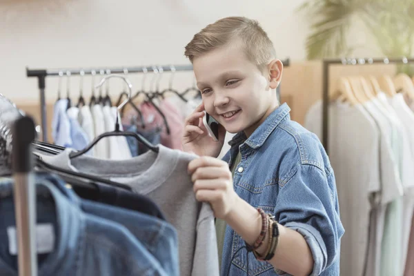 Усміхнений Хлопчик Використовує Смартфон Тримаючи Тканину Руці Магазині — стокове фото