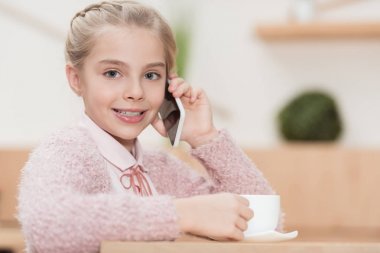 elinde Kupası ile oturma ve smartphone kullanarak gülümseyen çocuk  