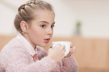 çok güzel çocuk üzerinde kahve Kupası'nda kafede otururken üfleme 