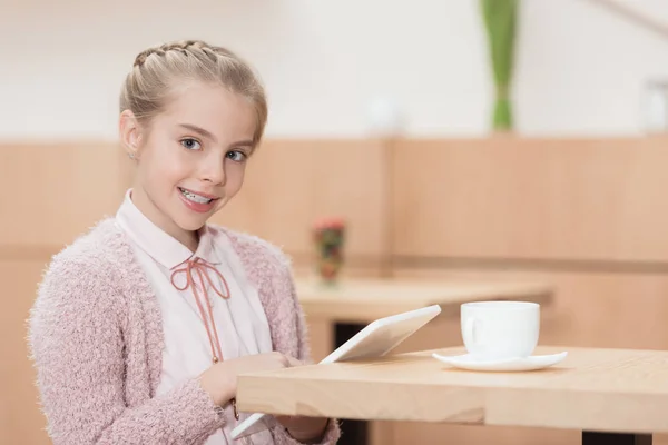 Uśmiechnięte Dziecko Cyfrowego Tabletu Patrząc Kamery Siedząc Przy Stole — Zdjęcie stockowe