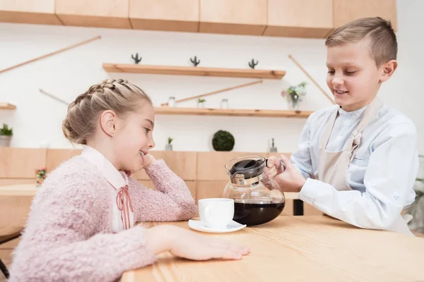 Băiat Care Ține Oală Cafea Mâini Timp Copilul Stă Masă — Fotografie de stoc gratuită