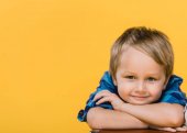Porträt eines lächelnden kleinen Jungen im Hemd, der isoliert auf gelb in die Kamera blickt