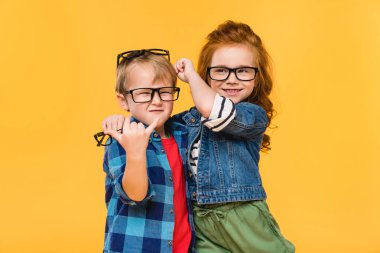 portrait of smiling kids in eyeglasses isolated on yellow