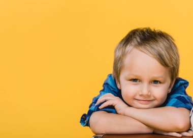 portrait of smiling little boy in shirt looking at camera isolated on yellow