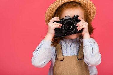 fotoğraf makinesi üzerinde pembe izole tutan çocuk gizlenmiş görünümünü