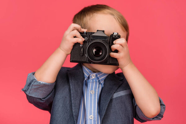obscured view of kid holding photo camera isolated on pink