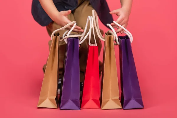 孩子和购物袋在粉红色隔离的部分视图 — 图库照片