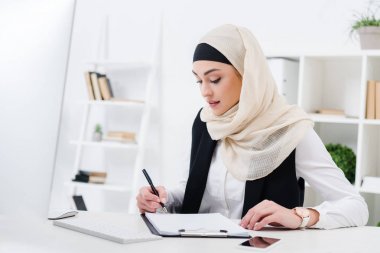 Kağıtları işyerinde imza odaklı Müslüman işkadını portresi