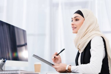 hijab belgelerle işyeri ofis içinde gülümseyen iş kadını yan görünüm