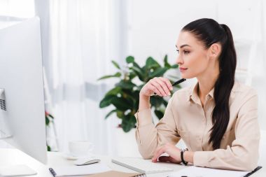 office iş yerinde bilgisayar ekranına bakarak gülümseyen iş kadını