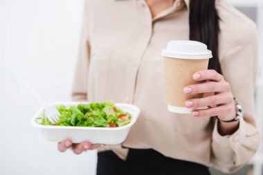 cropped shot of businesswoman with take away food and coffee to go in office