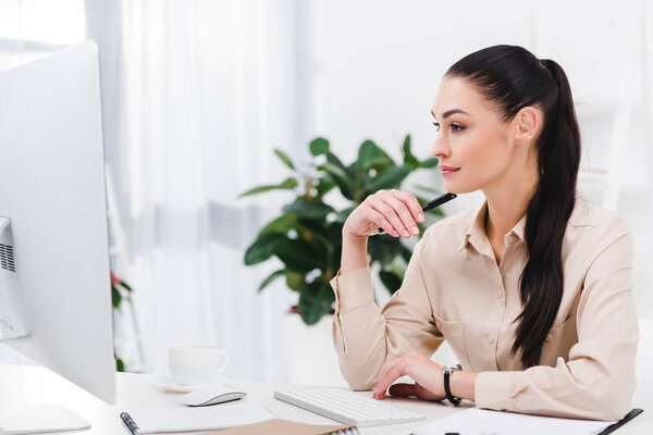 smiling businesswoman looking at computer screen at workplace in office