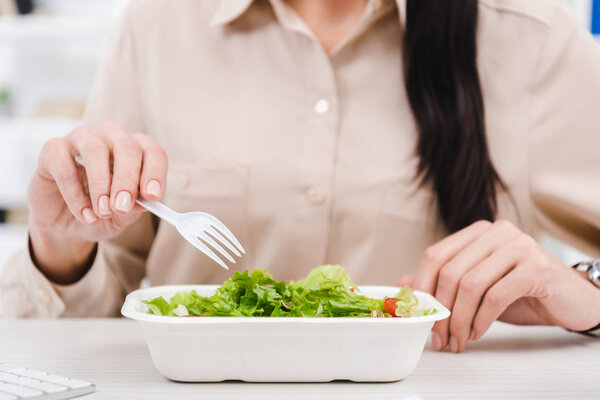 partial view of businesswoman with take away food at workplace in office