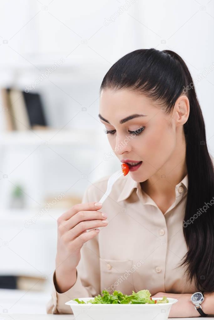 portrait of businesswoman eating take away salad for lunch in office
