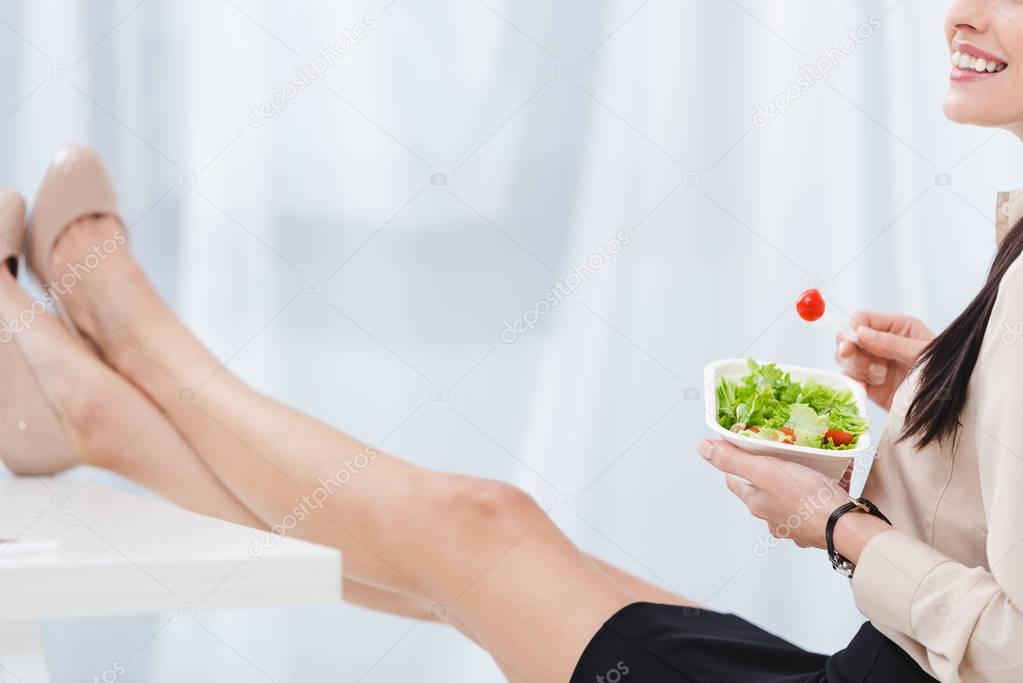 partial view of businesswoman with take away food at workplace in office