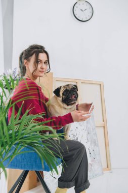 Tablet ve sarılma pug köpek evde kullanan çekici genç kız