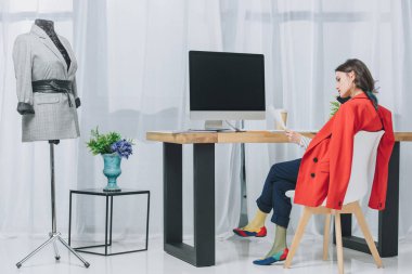 Bilgisayarla çalışma masasının telefonda konuşurken çekici genç kız