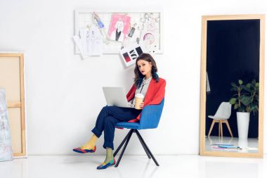 Dizüstü bilgisayarda çalışan ve kahve fincanı ışık studio tutan güzel Bayan