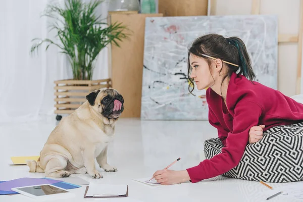 Wanita Cantik Bekerja Pada Ilustrasi Dan Melihat Anjing Pug Lucu — Stok Foto