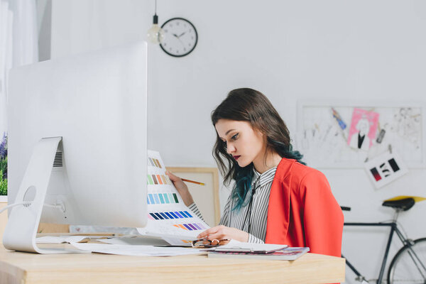 Женщина-дизайнер, работающая с палитрой за рабочим столом с компьютером
