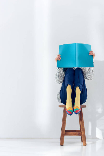 Girl sitting on chair and reading book