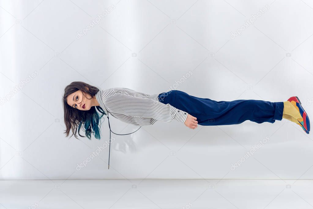 Pretty lady levitating on white wall background