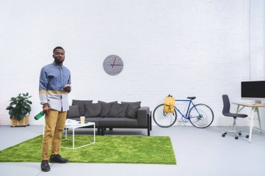 Afrika kökenli Amerikalı adam akıllı telefon ve bira şişesi holding modern Odaya
