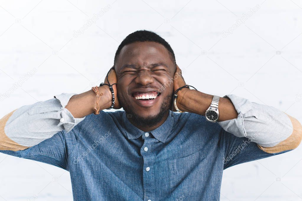 Young man laughing and covering ears