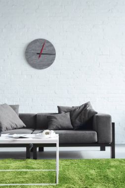 Cozy interior with modern grey sofa and clock on wall clipart