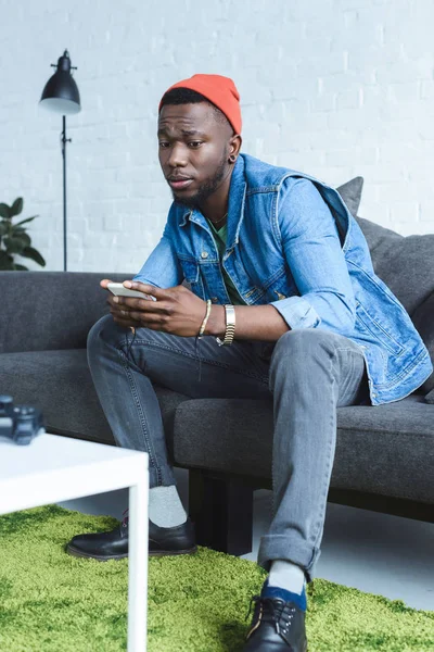 Hombre Afroamericano Sentado Sofá Usando Teléfono Inteligente — Foto de stock gratis