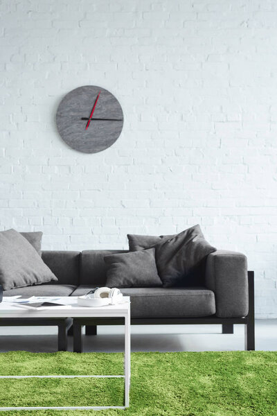 Cozy interior with modern grey sofa and clock on wall