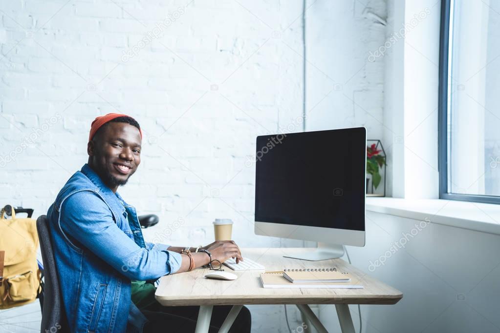 Handsome african american man working by table with computer