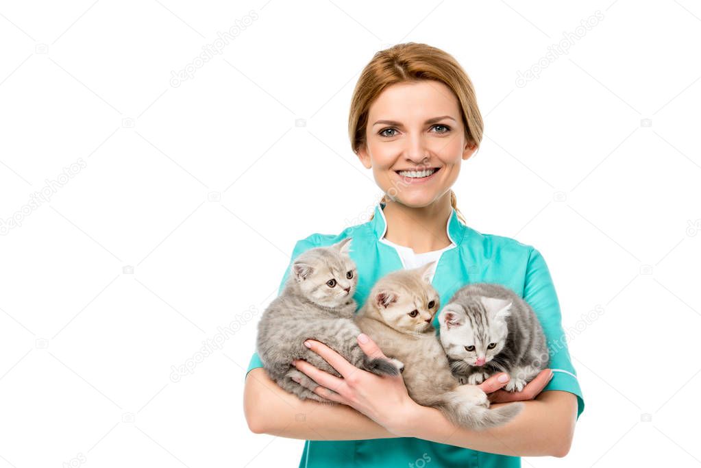 beautiful young veterinarian holding adorable kittens and smiling at camera isolated on white