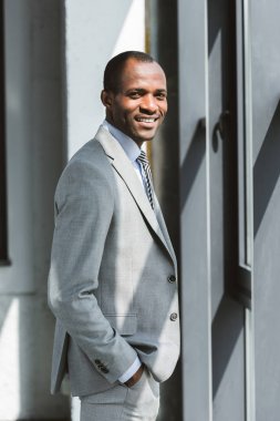 elle cebinde duran ve kameraya gülümseyen yakışıklı genç Afro-Amerikalı işadamı portresi
