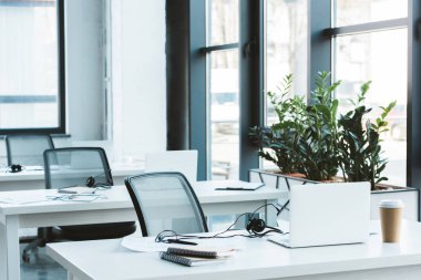 headsets and laptops on tables in modern office  clipart