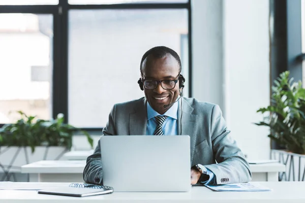 Sorridente Empresário Afro Americano Óculos Fone Ouvido Usando Laptop Escritório — Fotografia de Stock