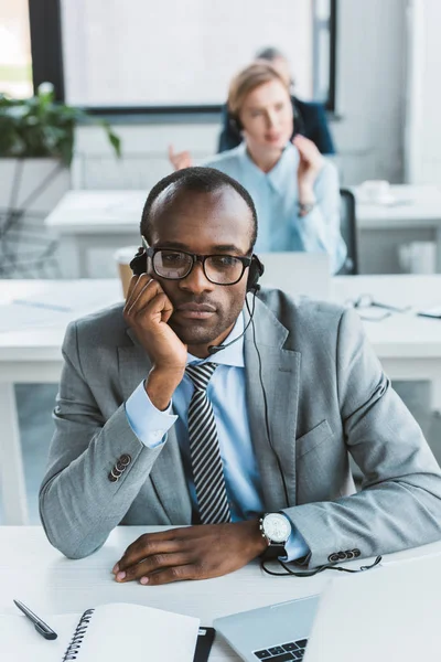 Young African American Businessman Eyeglasses Headset Sitting Hand Chin Office — Free Stock Photo