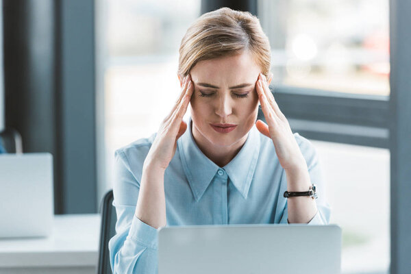 деловая женщина, страдающая головной болью во время работы с ноутбуком
