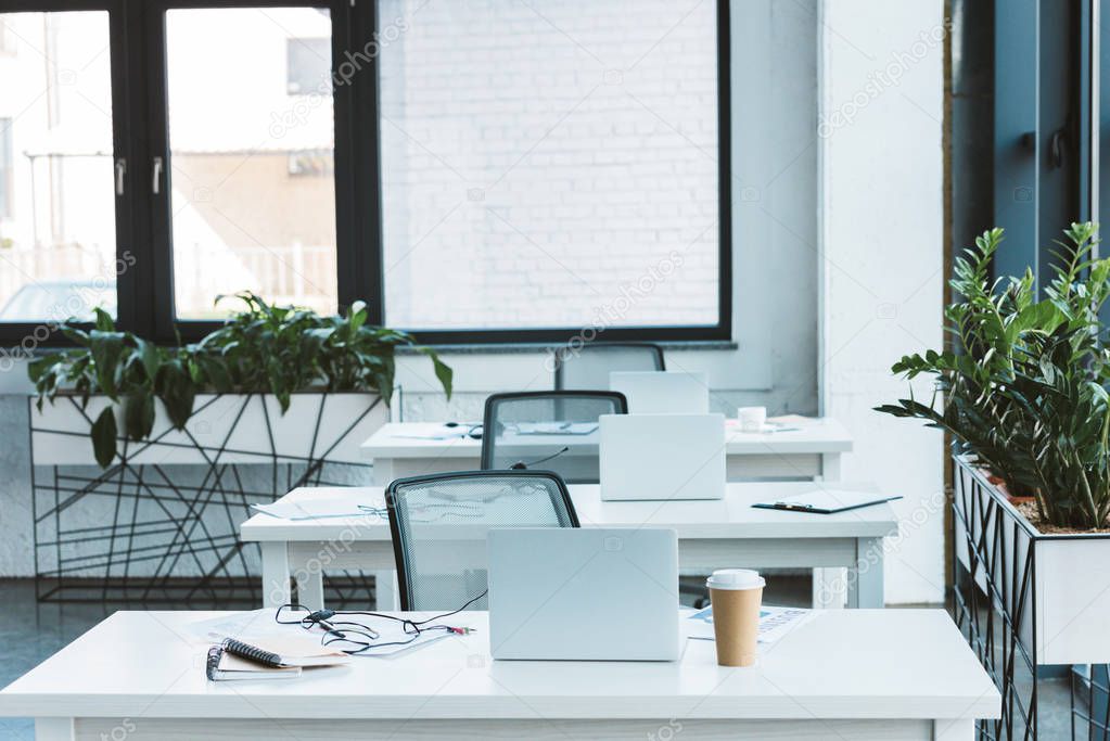 headsets and laptops on tables in light empty office 