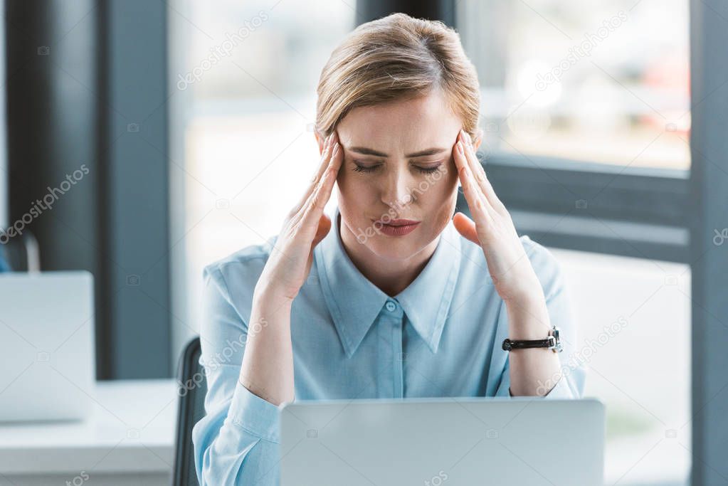 businesswoman suffering from headache while working with laptop