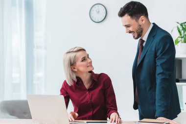Birbirimizi birlikte ofiste çalışırken gülümseyen genç iş arkadaşları