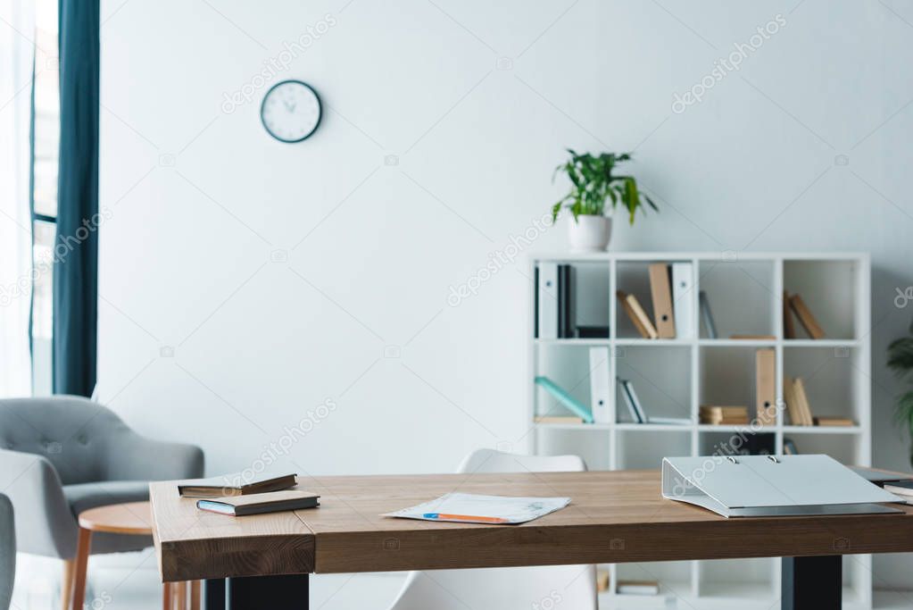 wooden table with folder, books and papers in modern office