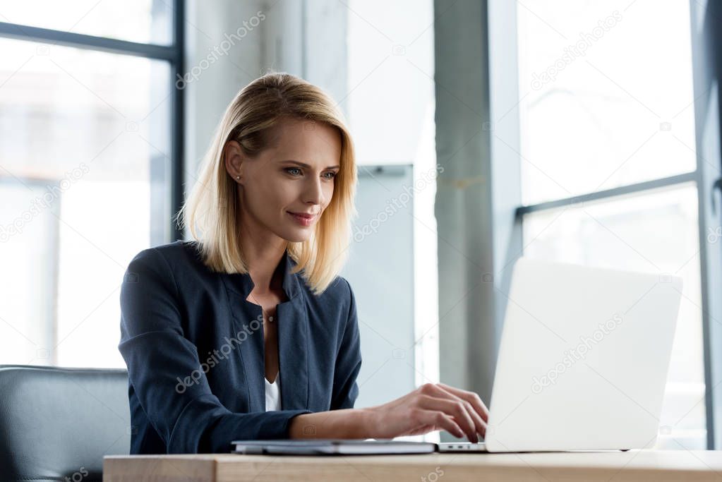 smiling professional businesswoman working with laptop in office