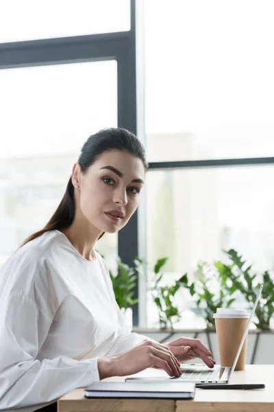 Hermosa Joven Empresaria Mirando Cámara Mientras Usa Ordenador Portátil Oficina — Foto de Stock